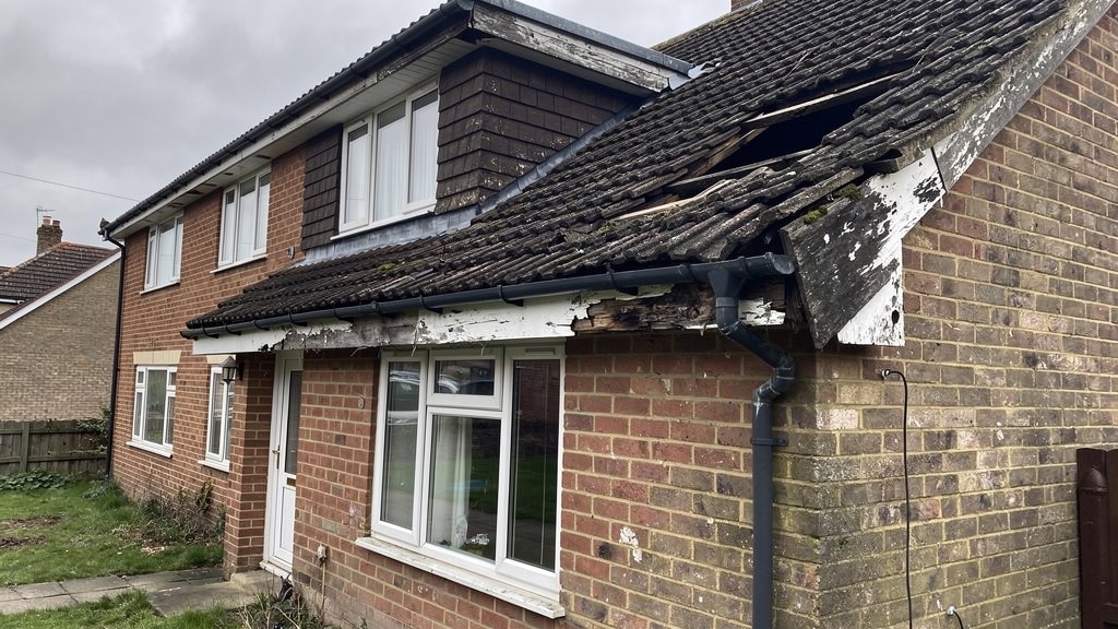 British house showing roof damage with missing tiles and sagging gutters